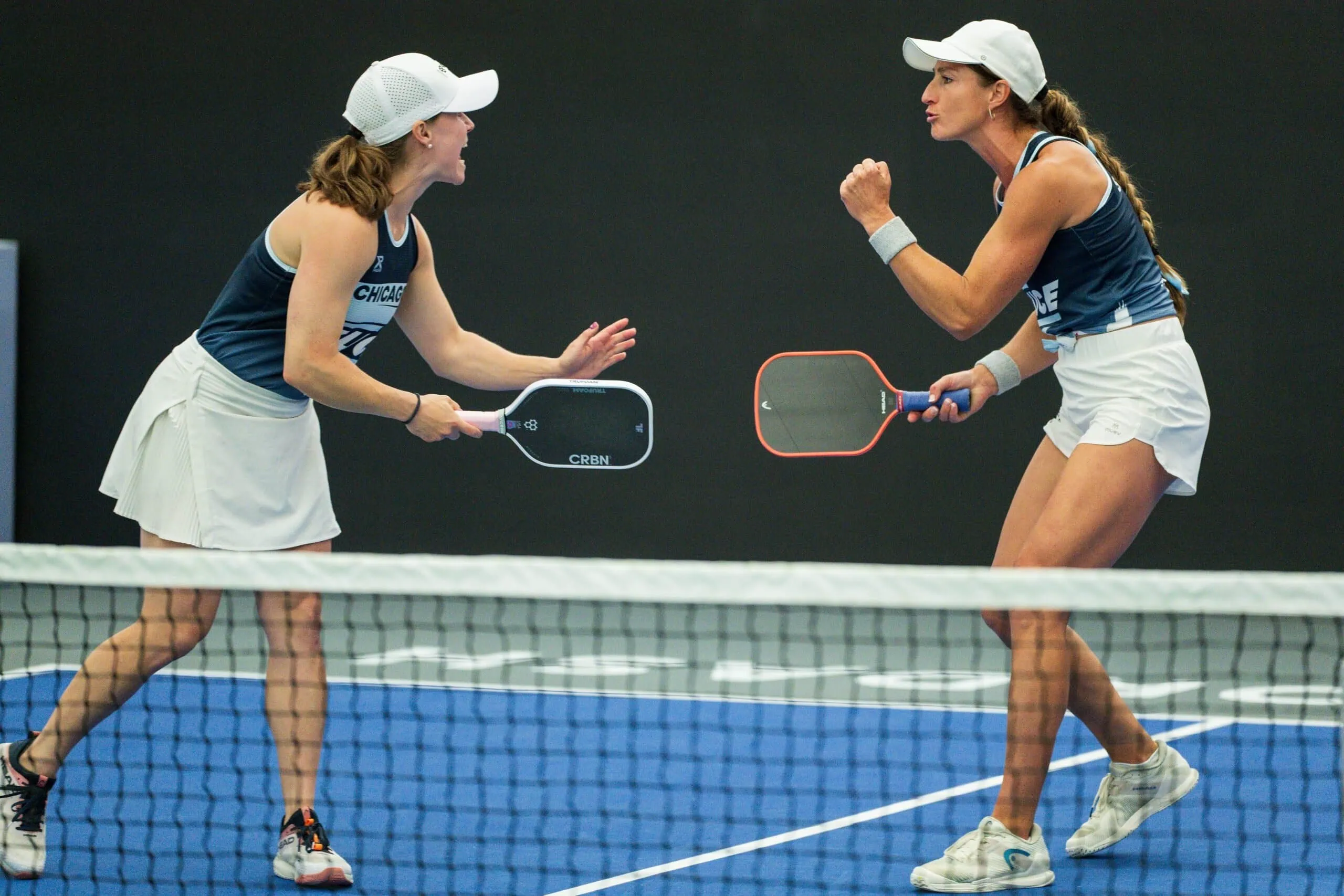 Two female players competing in a pickleball match at Major League Pickleball event.