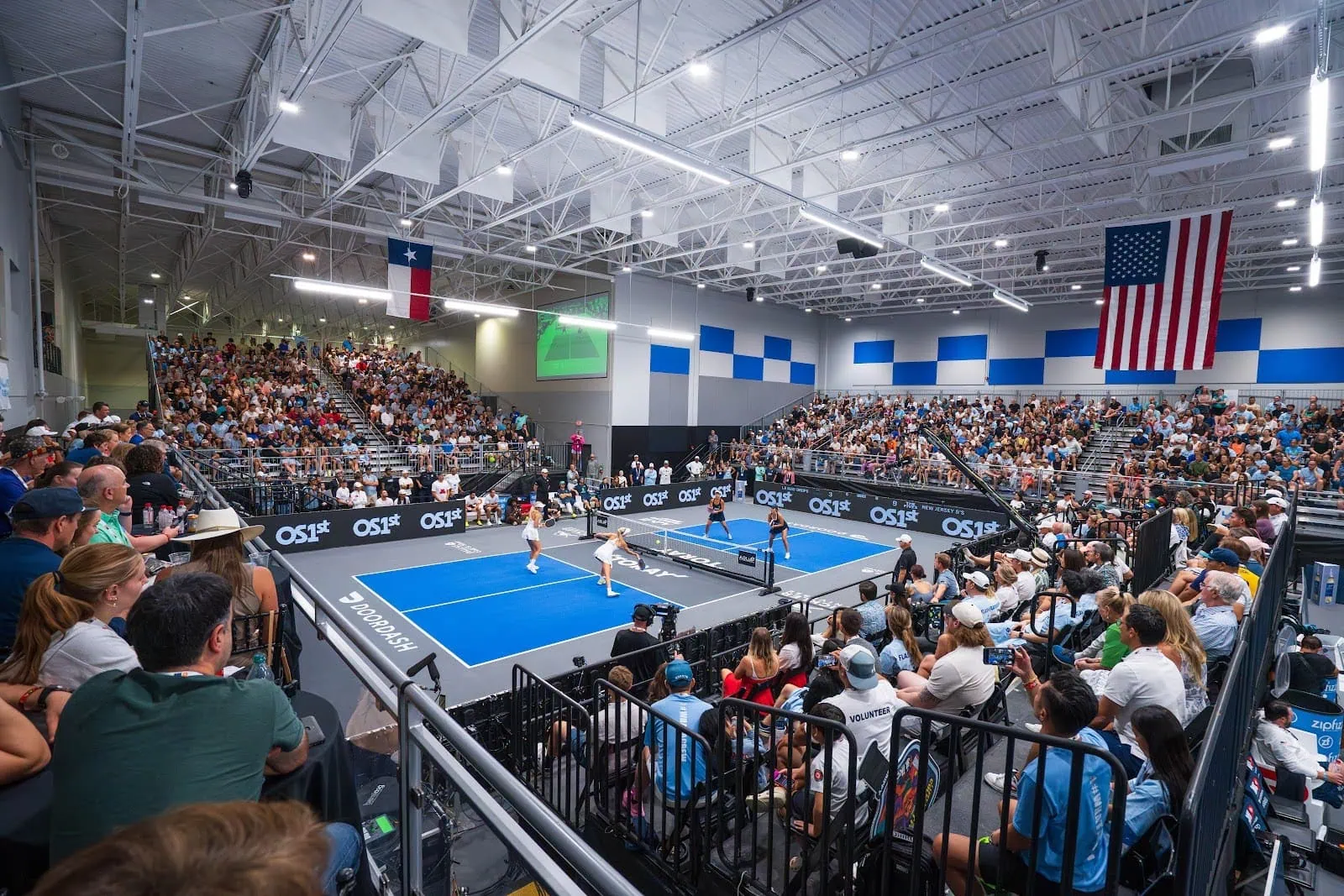 Indoor pickleball match with players and large audience.