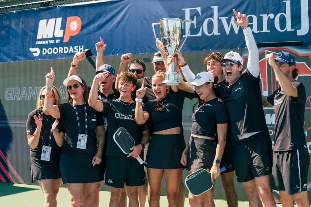 Pickleball players celebrating with trophy at Major League Pickleball event.
