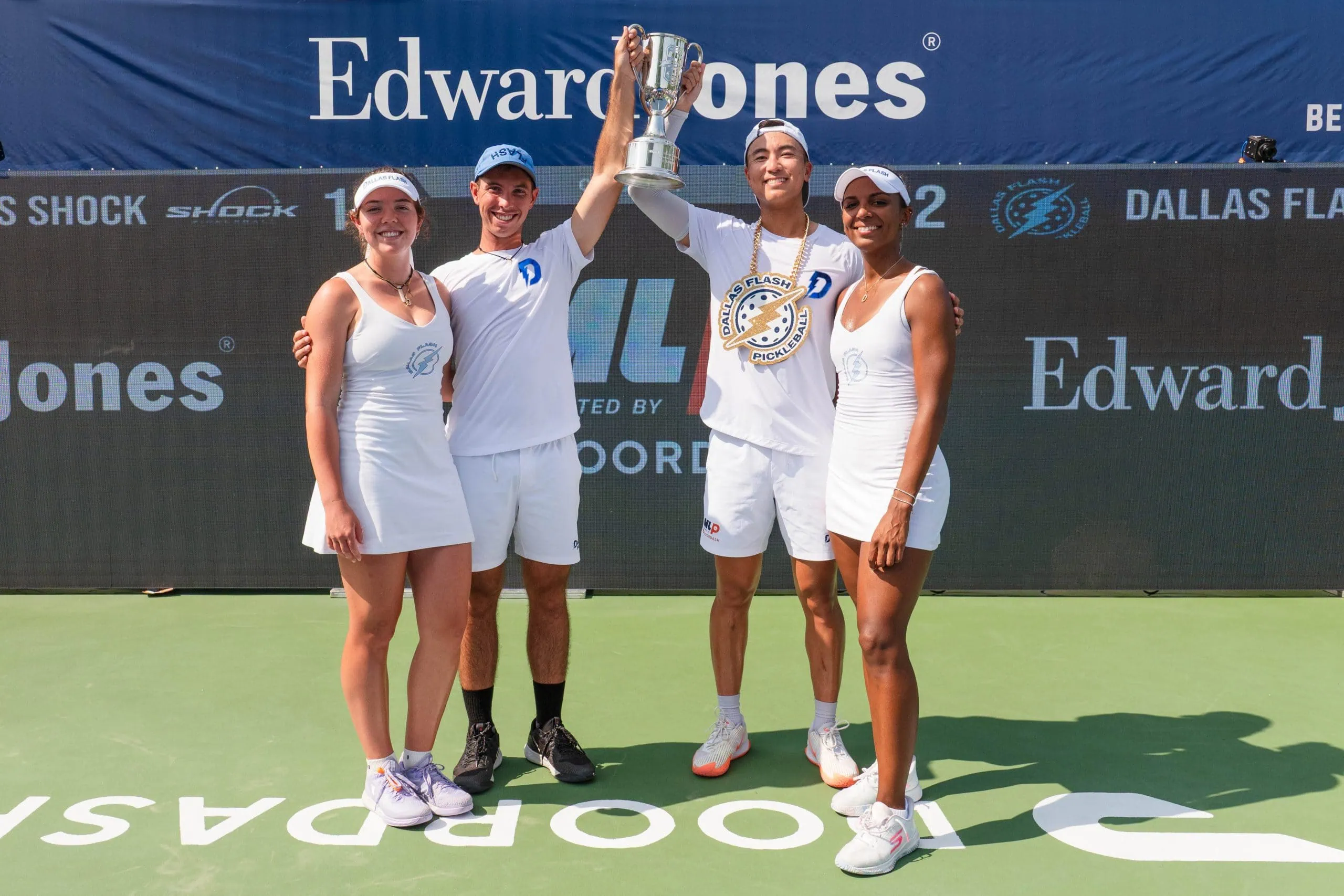 Team celebrating victory with trophy at Major League Pickleball event.