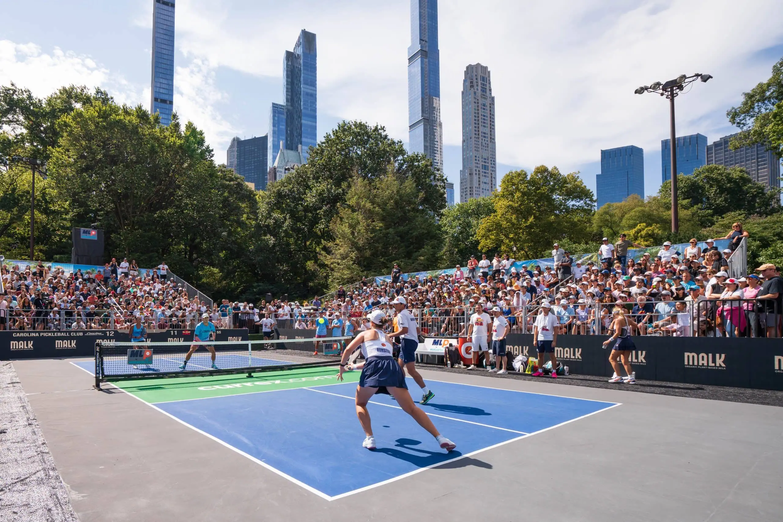 Exciting pickleball game in Central Park with city skyline backdrop.