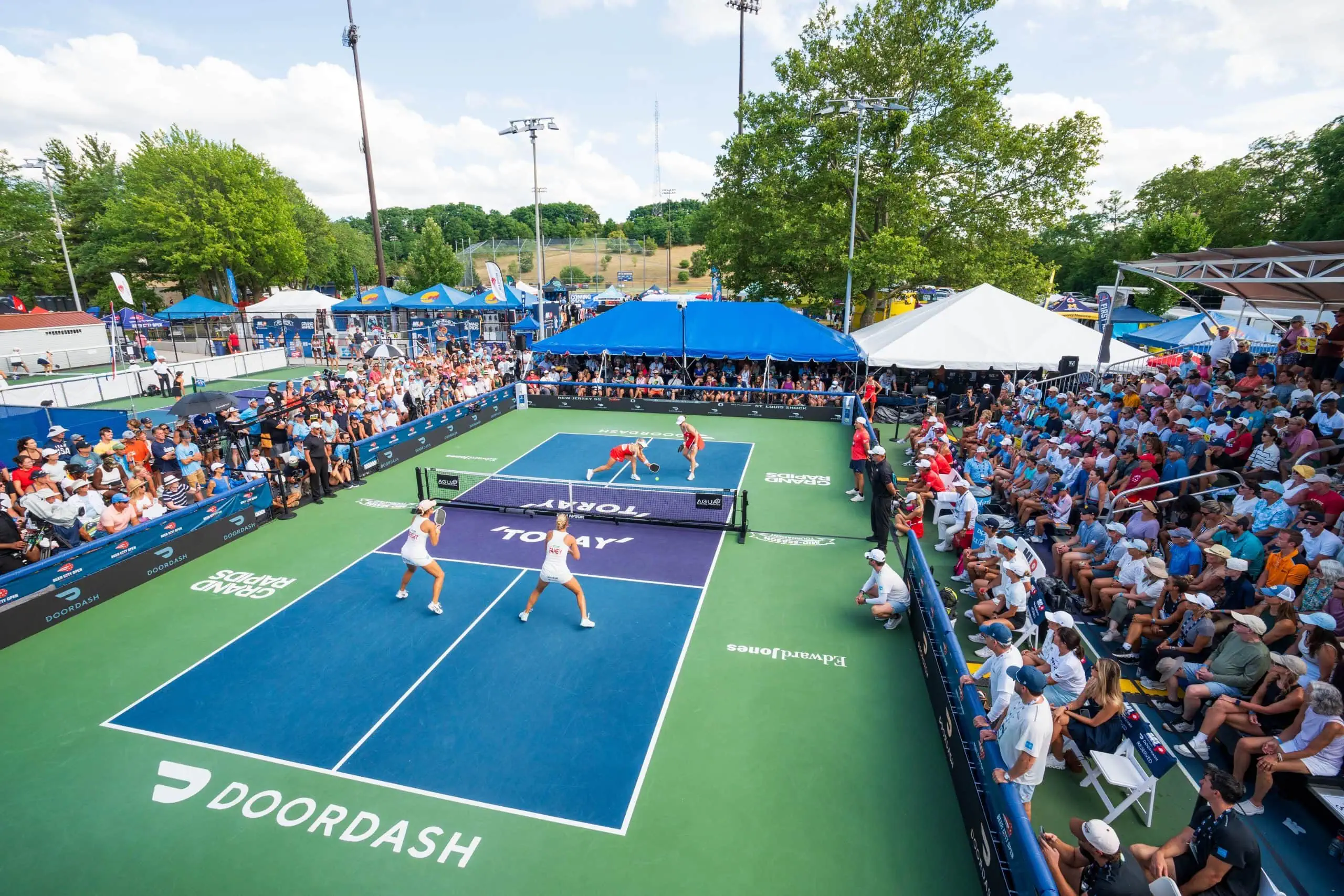 Pickleball players competing at Major League Pickleball event with large crowd and vibrant atmospher.