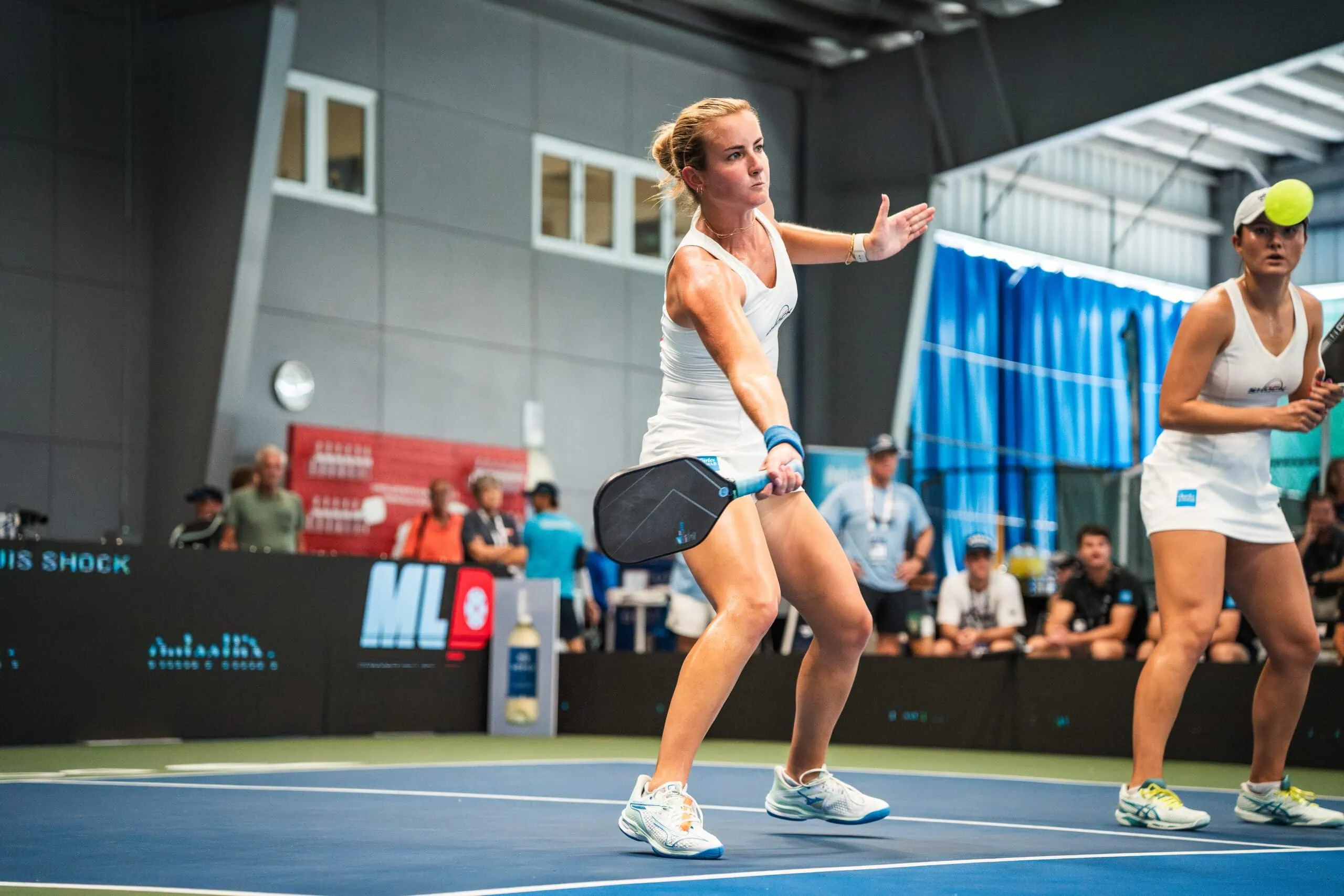Female player preparing to serve in pickleball match.