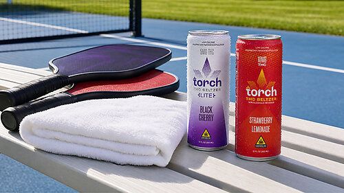 Torch THC beverages with pickleball paddles and towel on court bench.