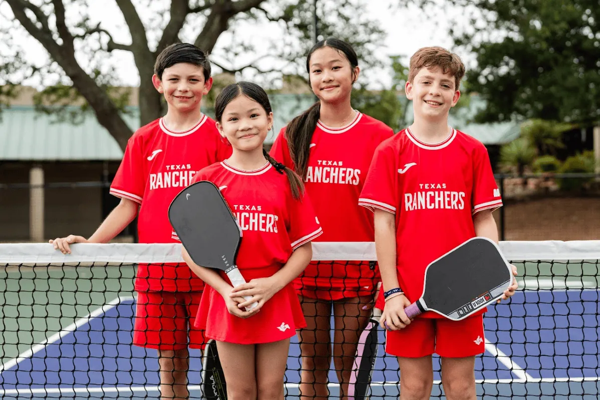 Young players holding paddles on a pickleball court during a Major League Pickleball match.